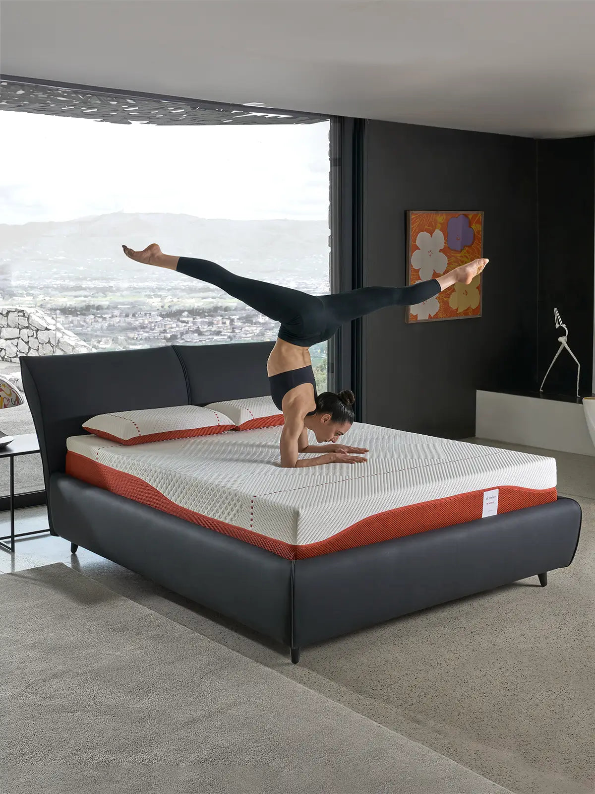 An athlete showcasing strength and balance on a Dorelan ReActive mattress, featuring a black bed frame in a stylish, light-filled bedroom.