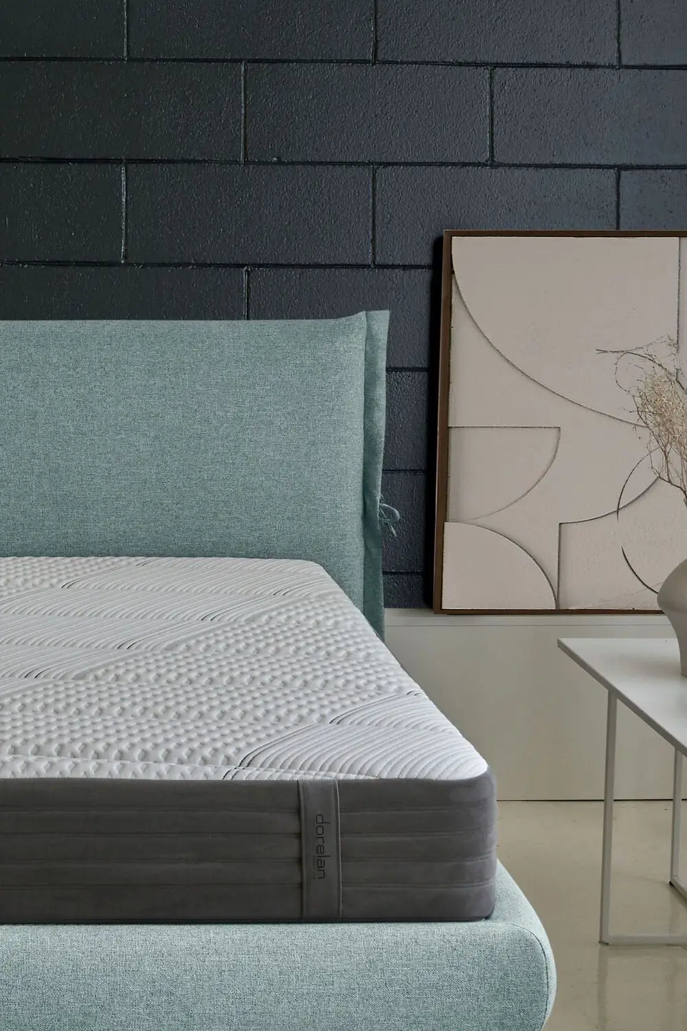 Close-up of the Dorelan Nube mattress with a teal bed frame and modern decor in the background.