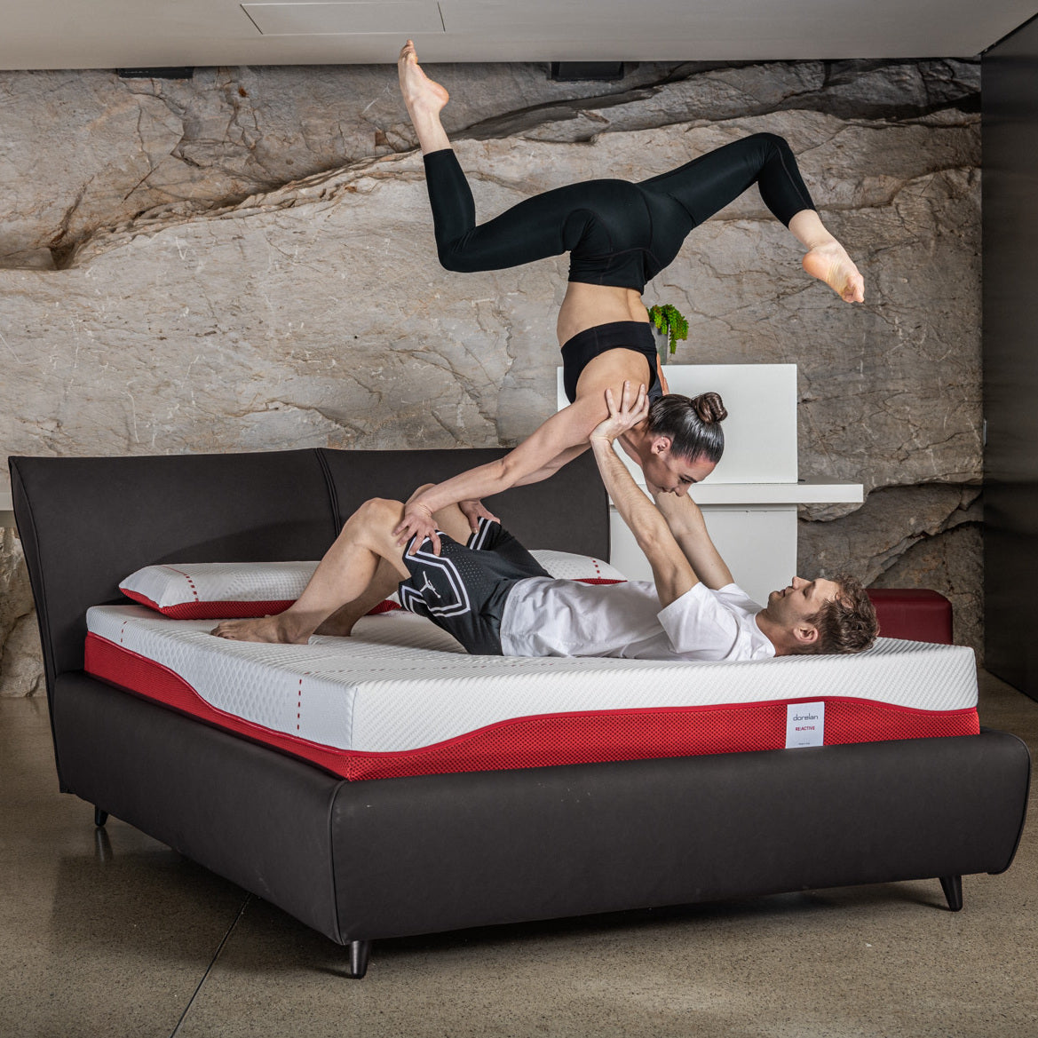 coppia fa esercizio fisico su materasso reactive per sportivi di dorrelan, in un letto nero sportivo.