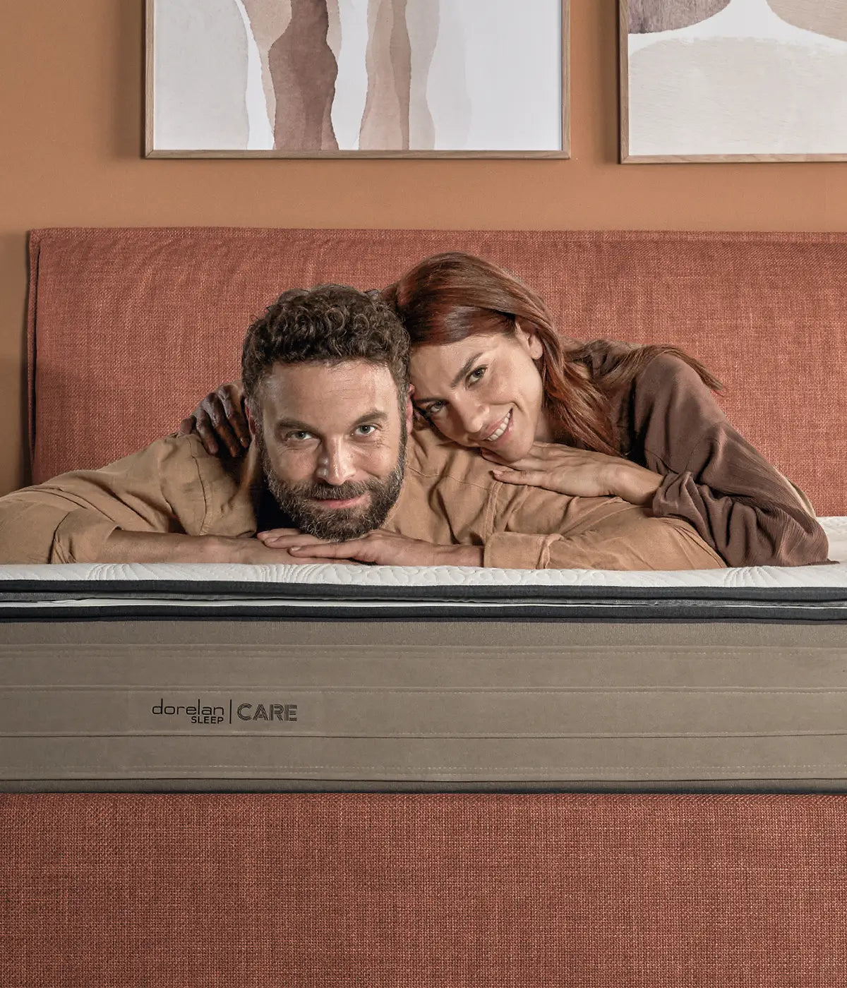 Materasso Dorelan Sleep | CARE con pillow-top; coppia rilassata in camera color terracotta.
