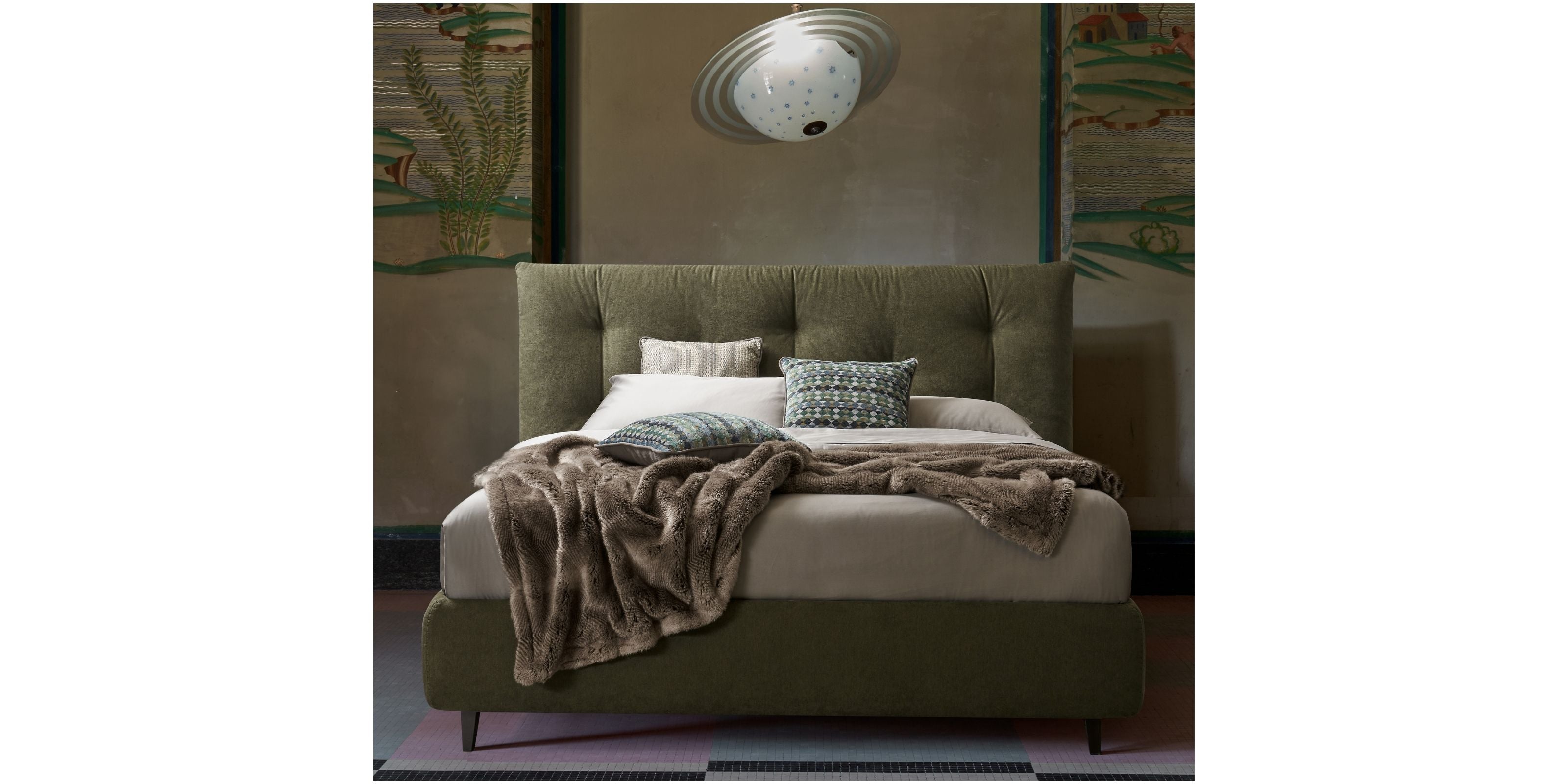 Letto imbottito verde oliva con testiera trapuntata, lenzuola grigie e cuscini decorativi in una camera elegante e moderna