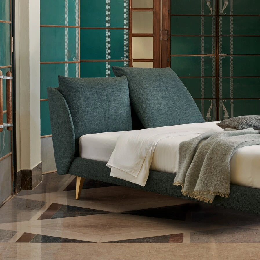 letto con testiera inclinabile, versatile che si adatta a tuto il giorno. è un letto blu con lenzuola bianche, senza contenitore