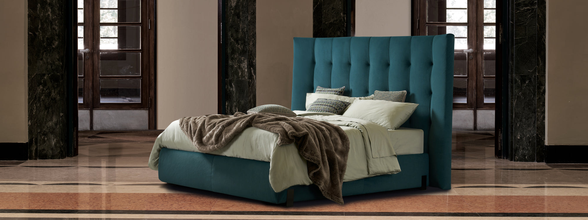 letto ottanio con grande testiera in un contesto elegante. le coeprte sono color menta