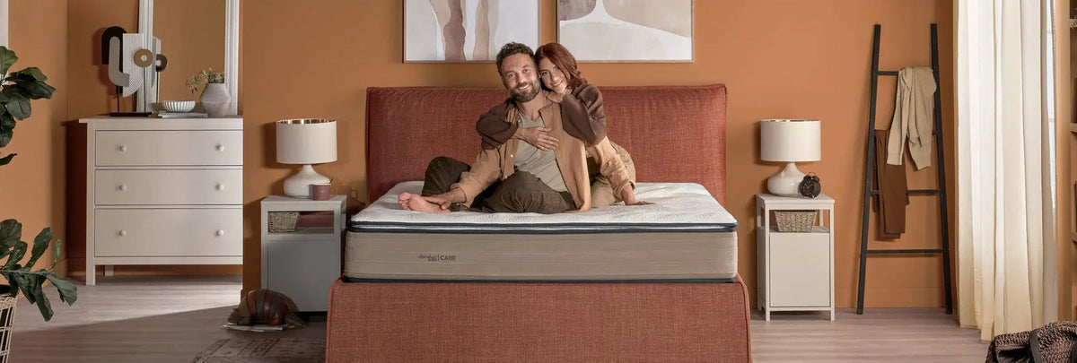 coppia su materasso matrimoniale francese di dorelan in una camera da letto dai toni arancione e marrone