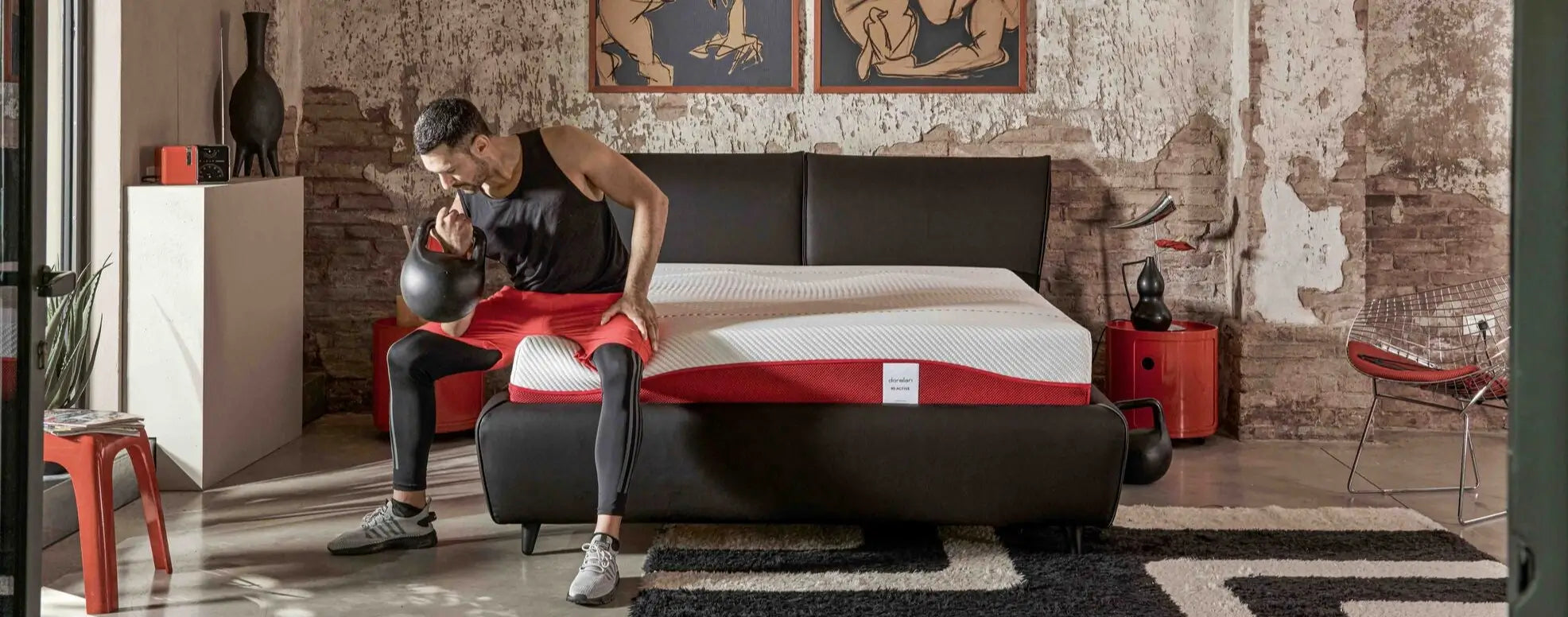 Uomo sportivo seduto sul letto con materasso Dorelan Re:Active, kettlebell in mano