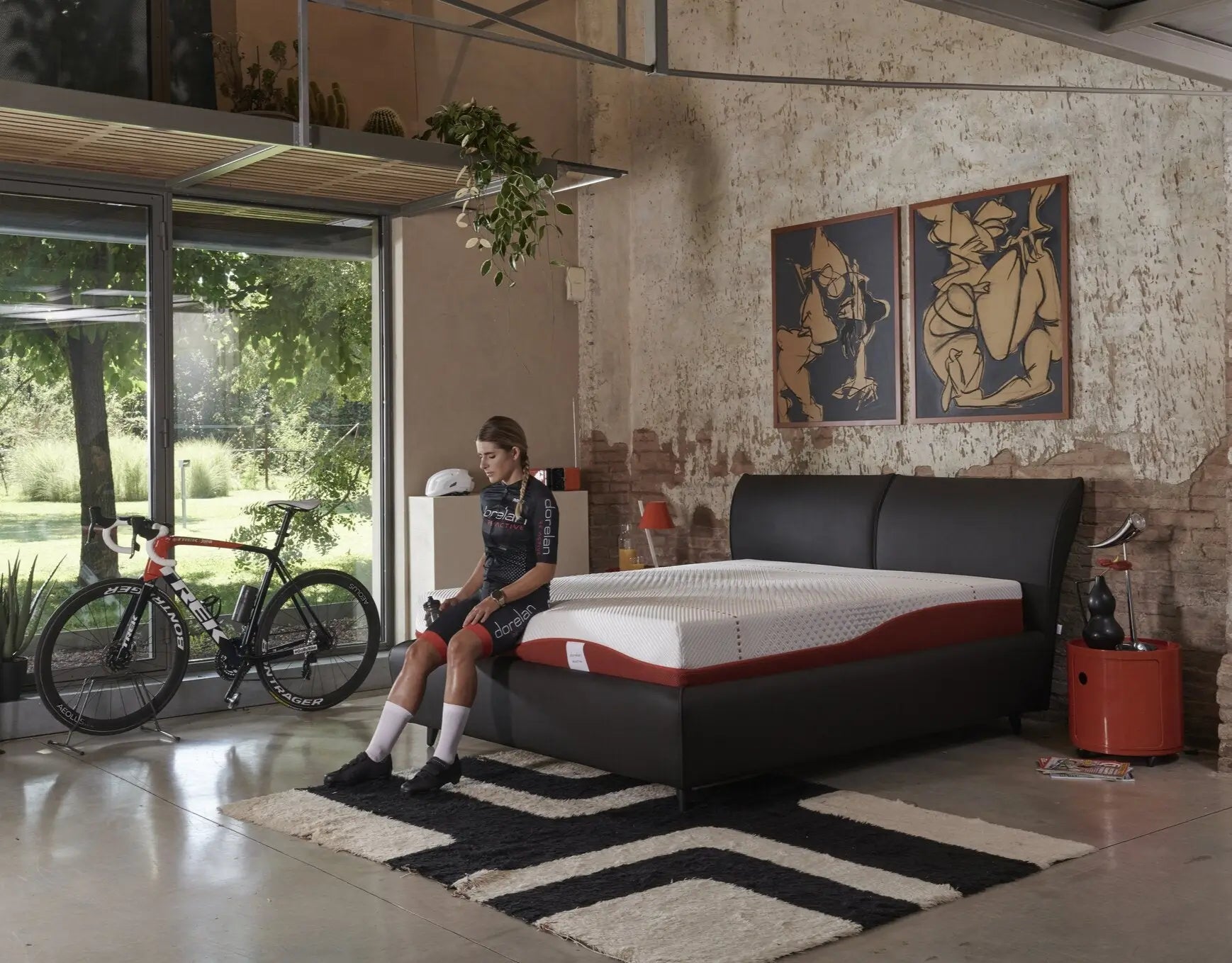 Recupero post-allenamento: atleta con bici da corsa accanto al letto e materasso Re:Active.