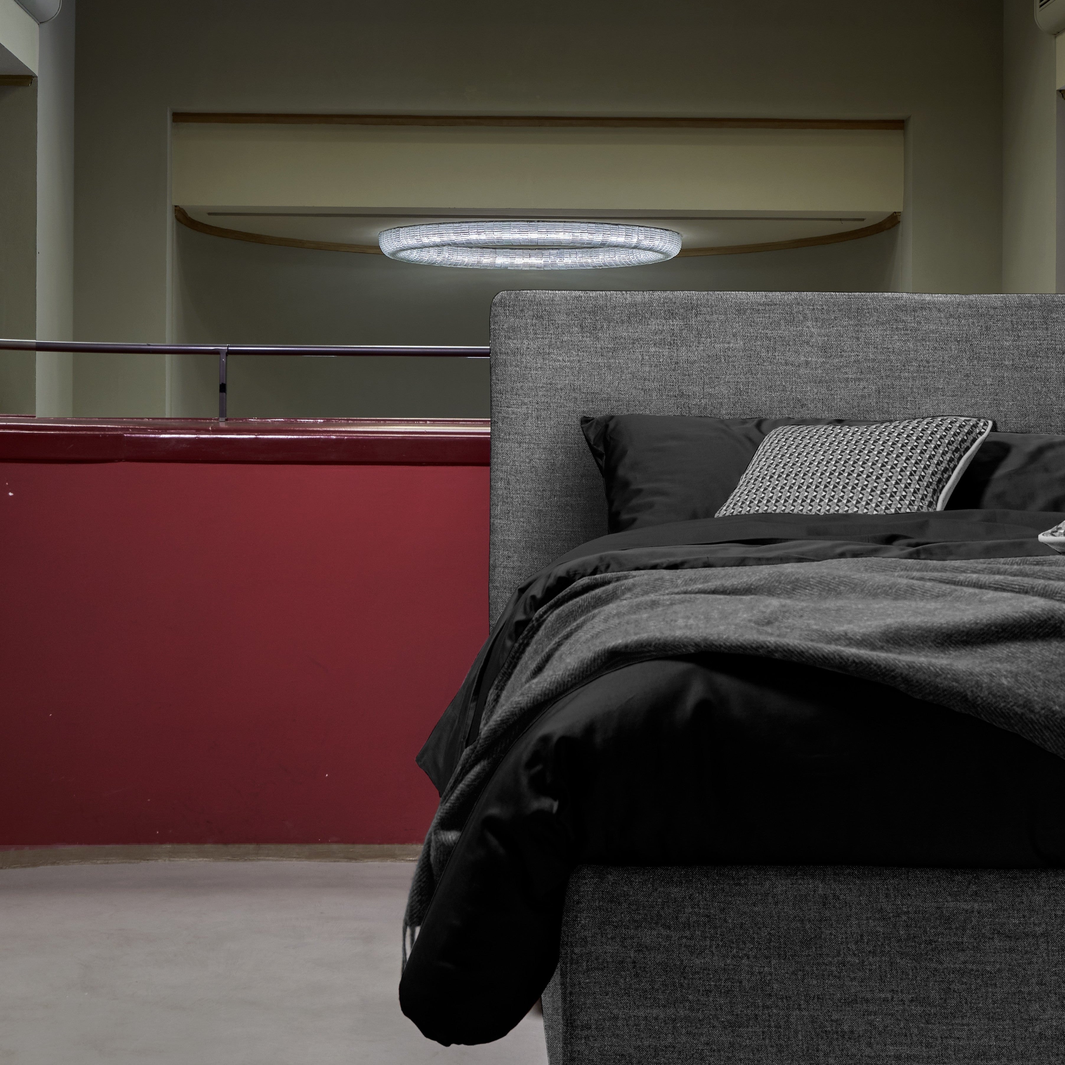 letto compatto macrodettaglio letto grigio con testiera piccola e lenzuola nere in un contesto architettonico antico