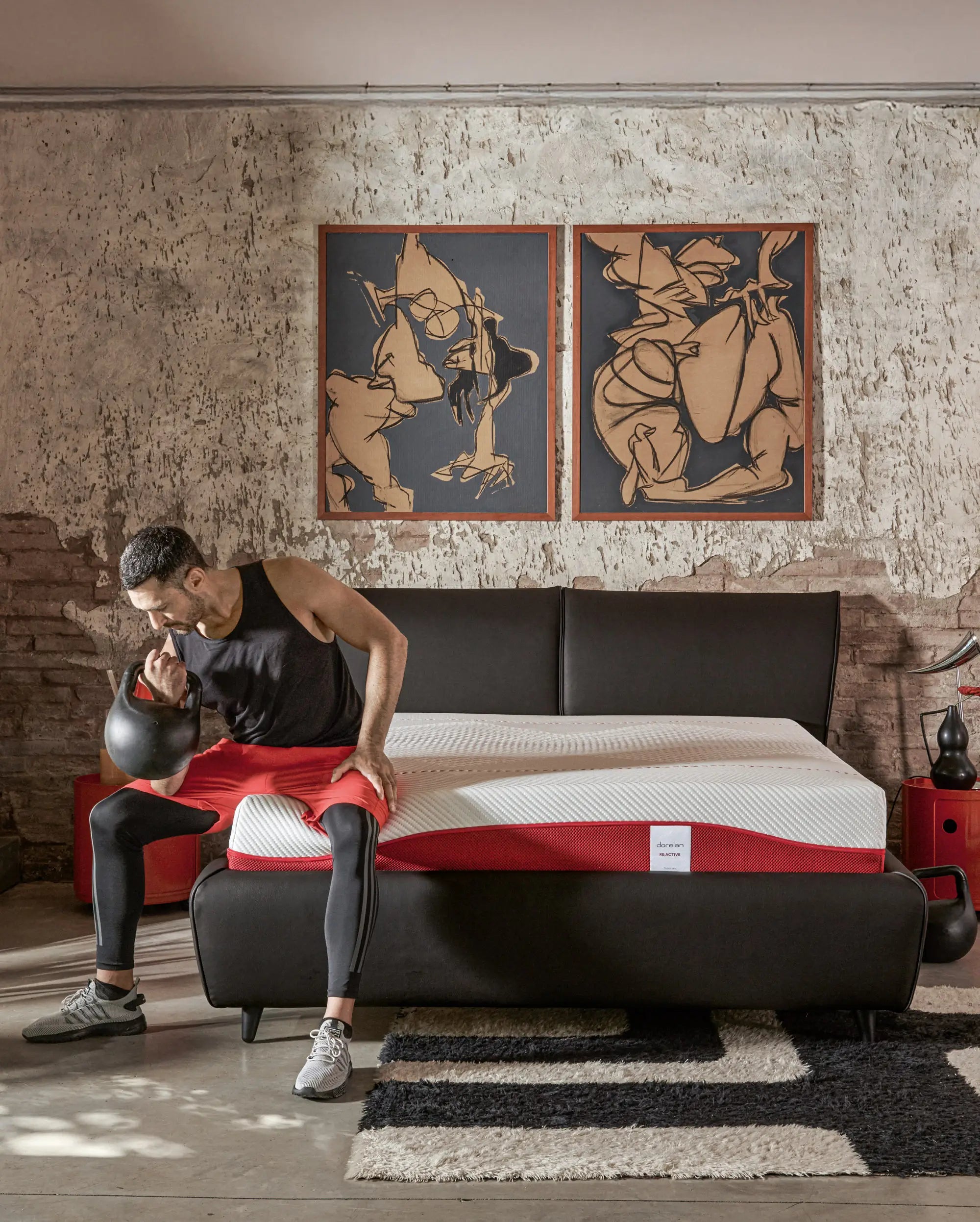 Uomo sportivo seduto sul letto con materasso Dorelan Re:Active, kettlebell in mano