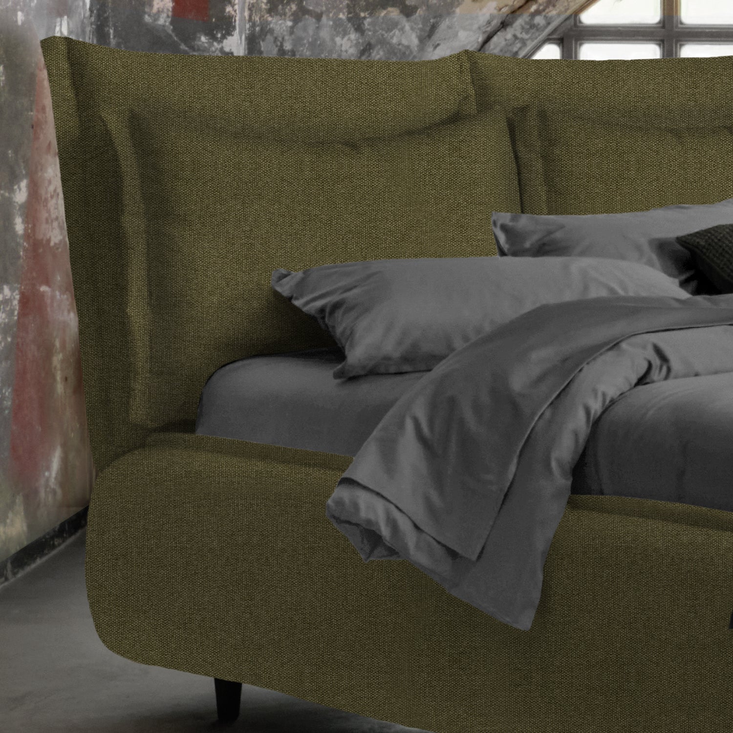 letto con doppia cuscinatura color verde bosco e lenzuola grigie