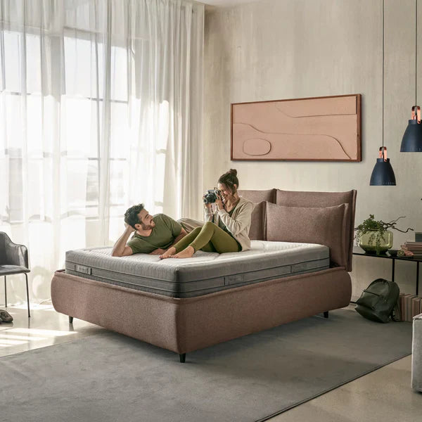 Coppia rilassata sul materasso Myform Arial Dorelan della Linea Innovative, in una camera da letto moderna con letto imbottito color terra.