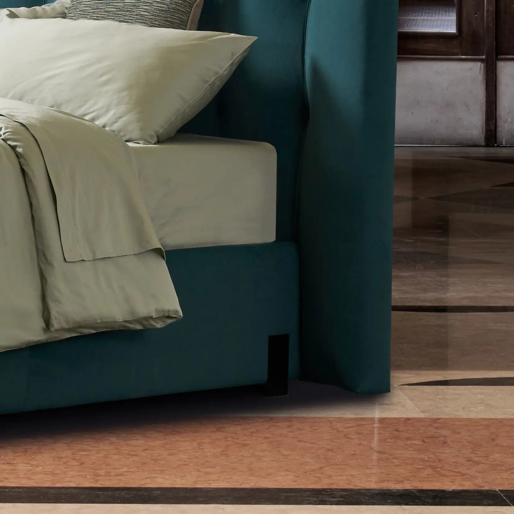 dettaglio di un piedino di design di un letto, nero e di forma rettangolare, che poggia su un eltto color aottanio