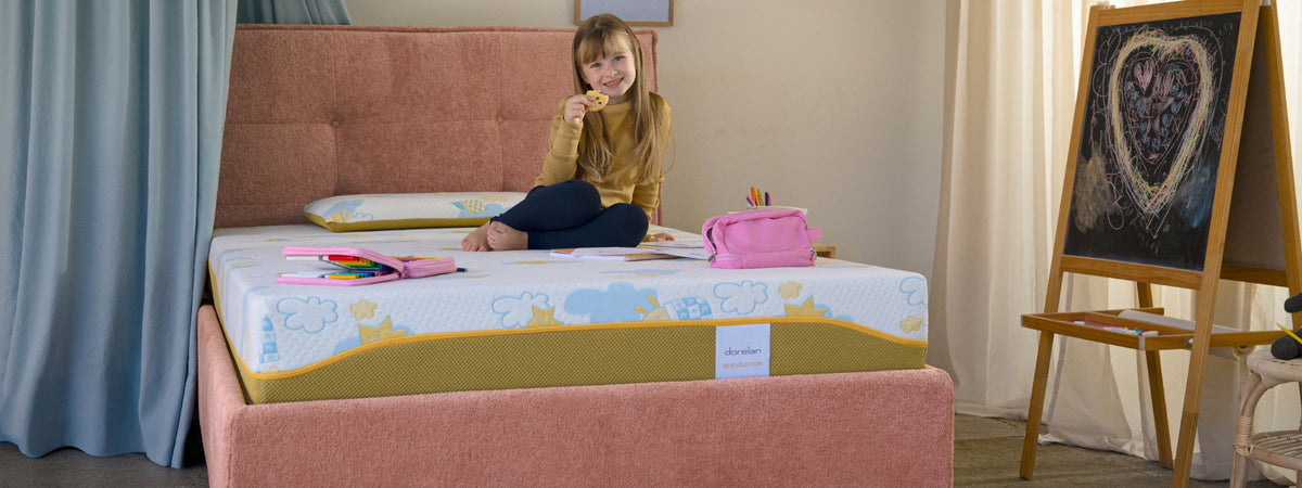 bambina mangia biscotto mentre fa i compiti sul suo materasso revolution di dorelan in una cameretta epr bambini con letto rosa