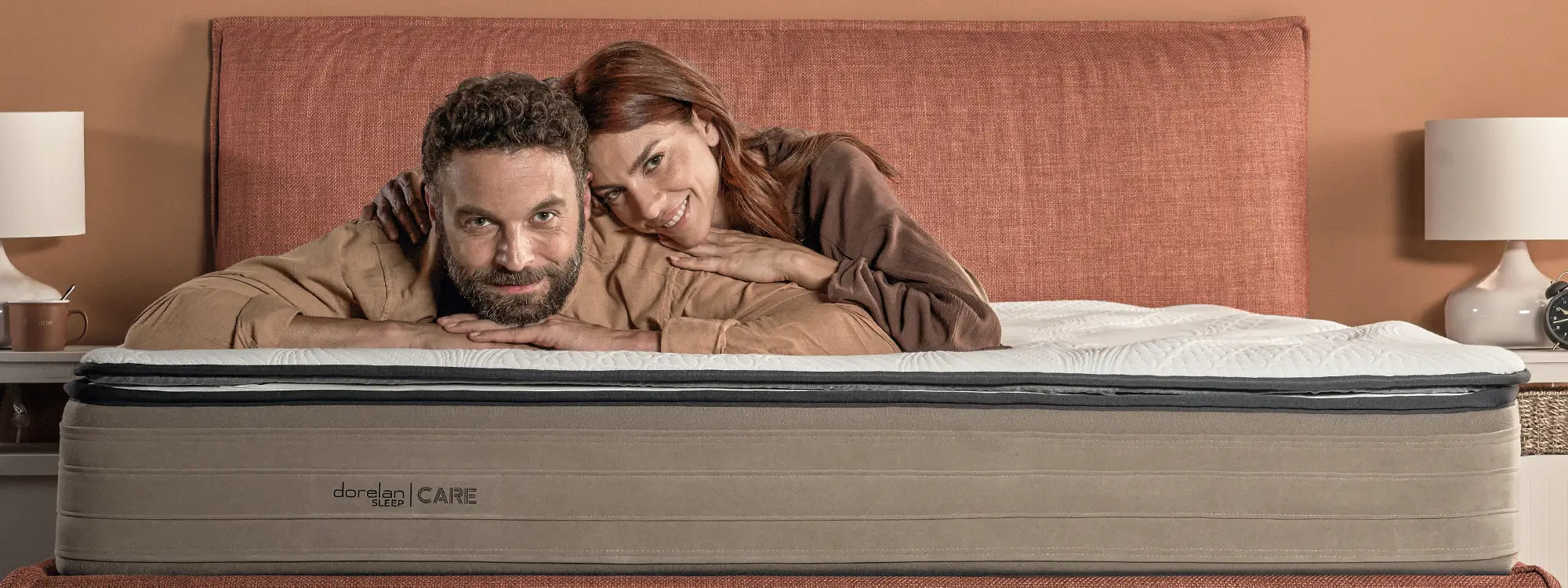 Materasso Dorelan Sleep | CARE con pillow-top; coppia rilassata in camera color terracotta.